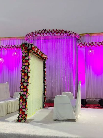A simple and elegant Nikah stage setup. It includes a floral partition for the bride and groom, with a larger backdrop and stage seating for family.
