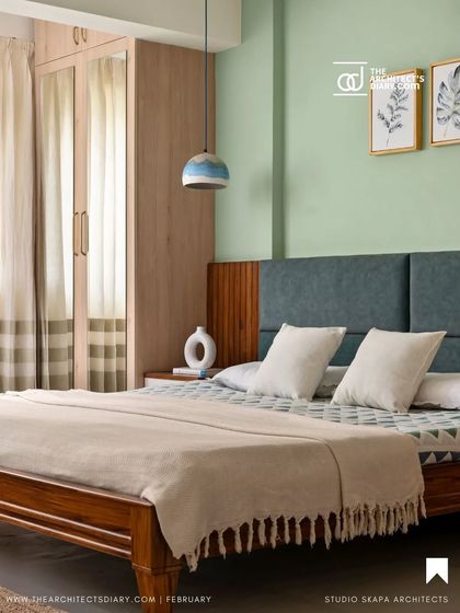 A magazine feature of the guest bedroom, showing the blend of the pastel green wall, teak wood bed, and custom ombre pendant light, creating a calm and inviting atmosphere.