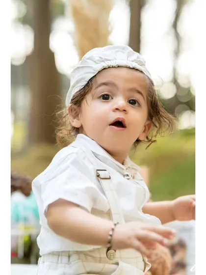 A sweet, curious expression captured in a close-up portrait. This little boy, part of a twin duo, looks on with wide-eyed wonder during his outdoor pre-birthday session.