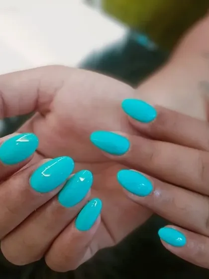 A vibrant and cheerful set of solid turquoise nails in a rounded oval shape, perfect for adding a pop of color.