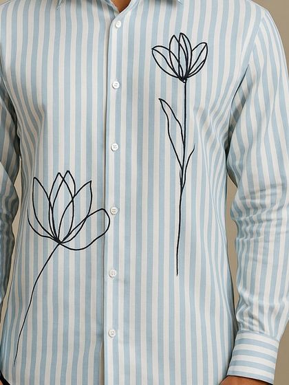 A close-up of the floral line art, showing the clean, minimalist style of the embroidery. This detail adds a touch of nature-inspired art to a classic striped shirt.