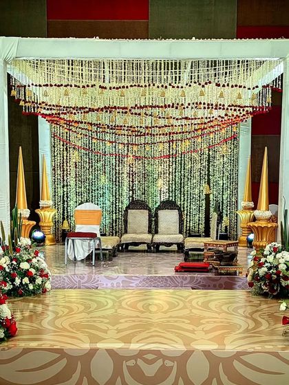 A traditional mandap setup with a canopy of hanging floral strings (lares). The simple white structure and classic seating arrangement make it a perfect choice for a sacred and timeless Hindu wedding ceremony.