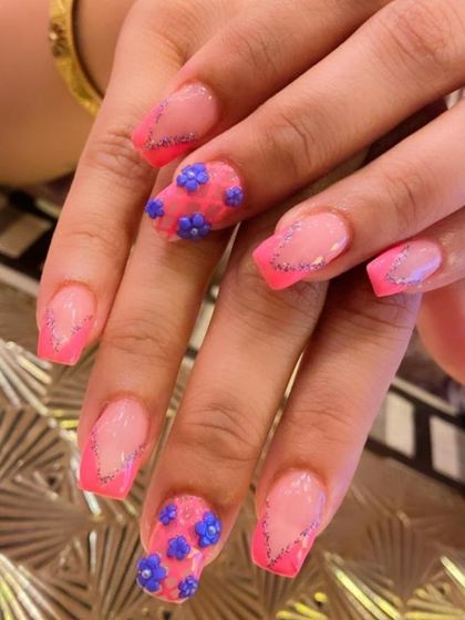 A vibrant and playful design with pink French tips outlined in silver glitter. The accent nails feature intricate 3D sculpted purple flowers for a fun, textured look.