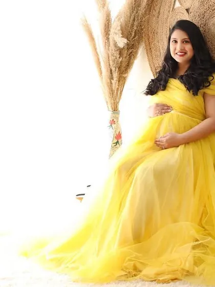 The light of a new life. This mom-to-be shines in a yellow tulle gown, seated in a bright and airy boho-themed corner of the studio.
