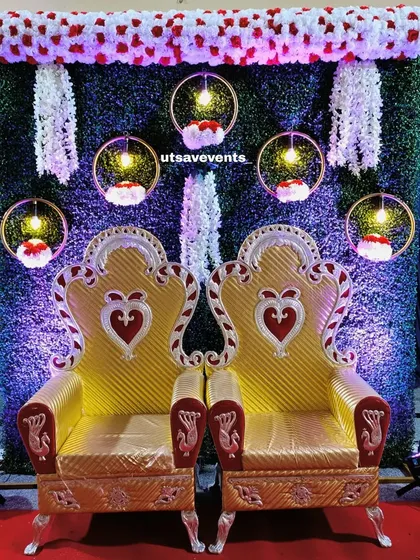 A simple yet beautiful engagement stage with two golden thrones. The greenery wall is decorated with hanging floral hoops and lights.