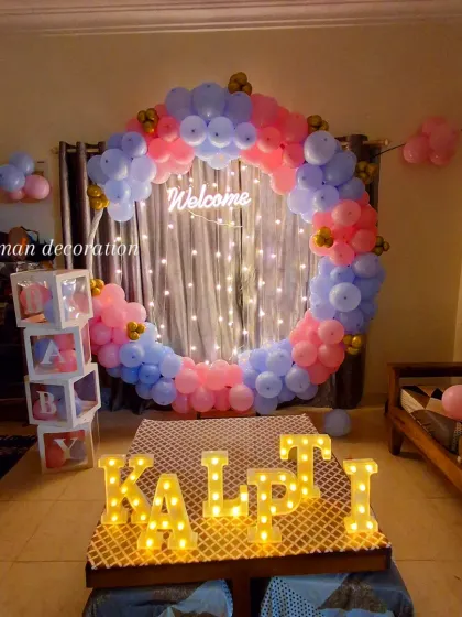 This "Welcome" decoration for a baby uses a mix of pink and blue balloons on a ring arch with fairy lights. The light-up letters and "BABY" blocks add a personal touch.