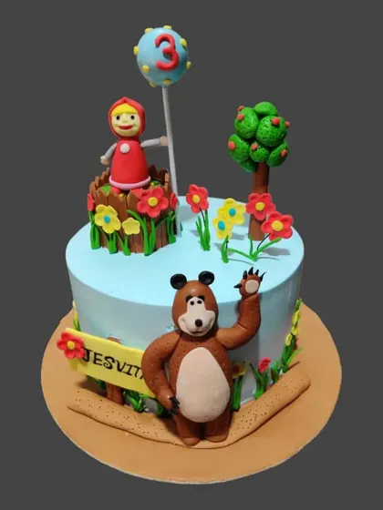 A playful Masha and the Bear cake, featuring the characters in a colorful garden setting with a tree and flowers.
