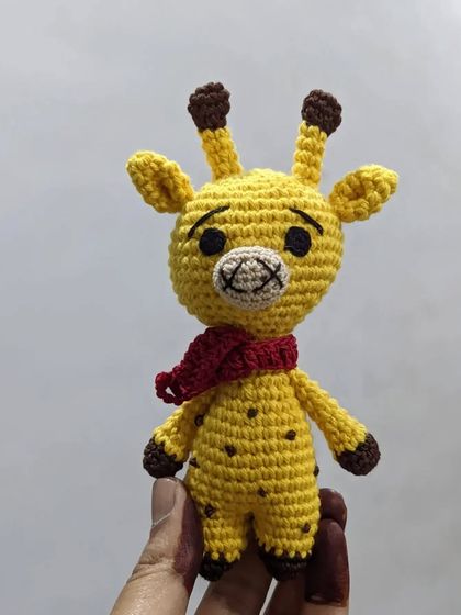 A little yellow giraffe with a red scarf, perfect for small hands.