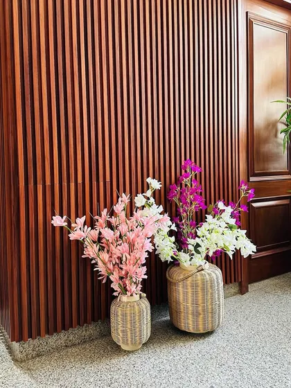 A detail shot focusing on the texture of the wood-fluted wall and the colorful artificial flowers that add a pop of color to the entrance.