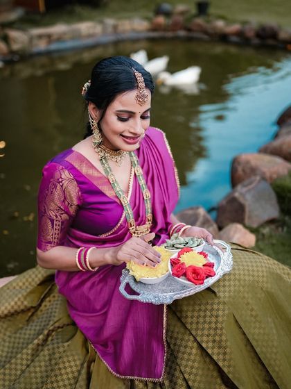 A close-up portrait of a woman in traditional attire for a festival shoot, holding a tray of flowers and offerings.