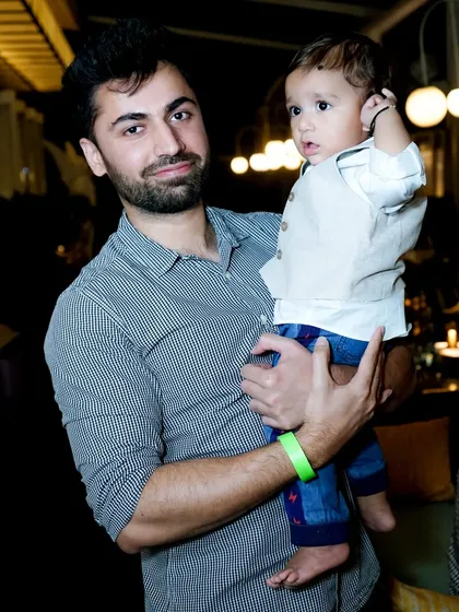 A candid shot of a father holding his young child at a family party. We document the special moments at your family events.
