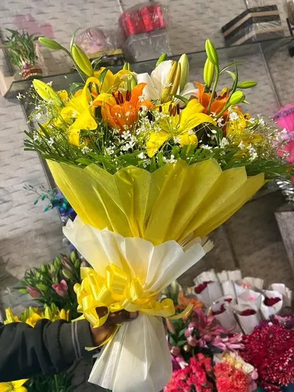 A bright and cheerful bouquet of fresh yellow and orange lilies, wrapped to highlight their vibrant colors. Lilies are a popular choice for birthdays and get-well-soon wishes.