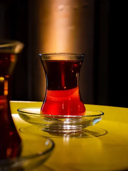 A beautiful shot of Turkish tea, with the light hitting the glass to create a jewel-like red glow. The focus is on the rich color and clarity of the tea.