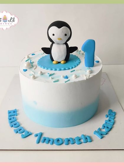 A sweet one-month milestone cake. This simple and adorable cake is topped with a cute fondant penguin, celebrating the first month of baby Kabir.