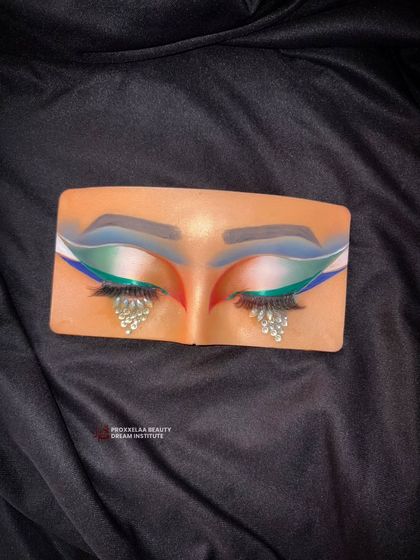 Because your eyes should always tell a story. This dramatic eye makeup on a practice board features bold colors and teardrop rhinestones.