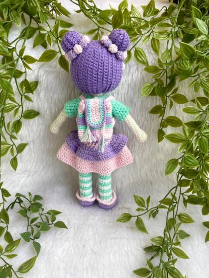 A beautiful doll with purple hair buns and a tutu dress. She also comes with a tiny backpack for her adventures. The striped stockings are attached, but her dress and shoes are removable.