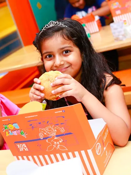 This young princess is enjoying a burger from her personal meal box. We ensure our food is both delicious and kid-friendly.