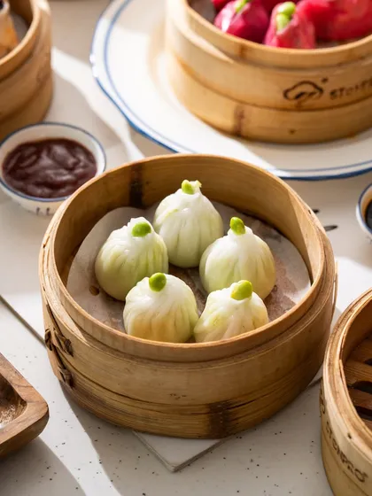 A close-up of delicate edamame and truffle dumplings. The focus is on the unique shape and the single edamame bean on top.