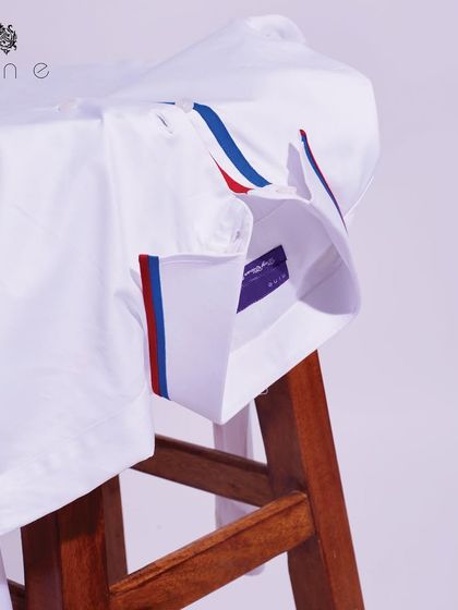 The classic white shirt with red and blue accents, draped to show its quality fabric and modern design details.