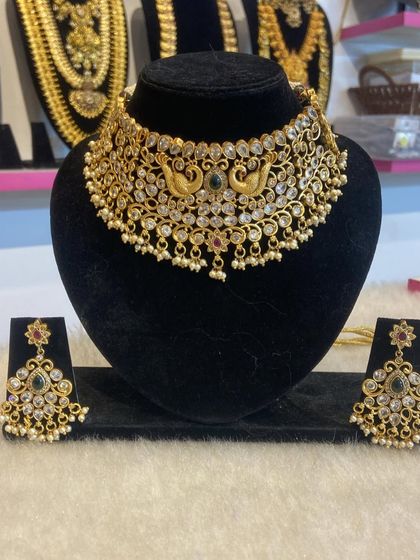 A peacock-motif choker with white stones and pearl drops. This elegant piece is a versatile rental option for various occasions.