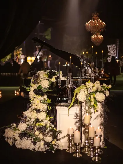 We see floral design as a form of sculpture. For this glamorous cocktail night, a grand piano became the canvas for a cascading waterfall of black and white florals, creating a dramatic and artistic focal point that exudes modern elegance.