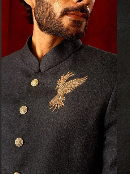 A close-up of the gold embroidered bird on our dark bandhgala. The intricate threadwork stands out against the textured fabric, a small detail that makes a big impact.