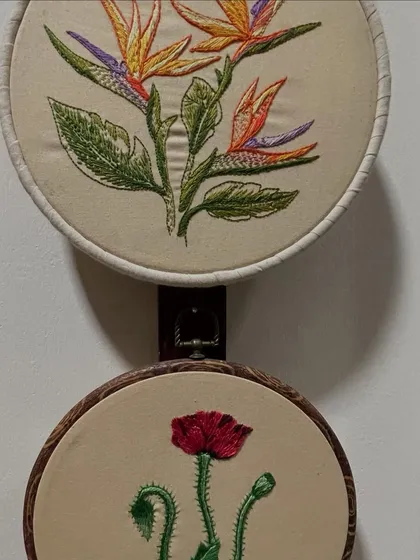 A collection of floral hoop art pieces. The top one features a Bird of Paradise, while the one below shows a delicate poppy. Each is a small celebration of nature's beauty.