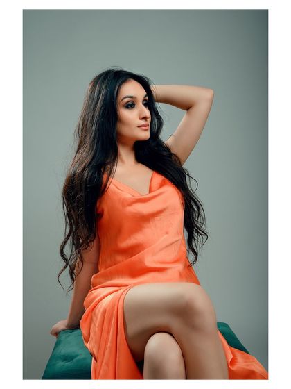 A glamorous portrait in a vibrant orange dress. The model's pose is confident and elegant, creating a striking image.