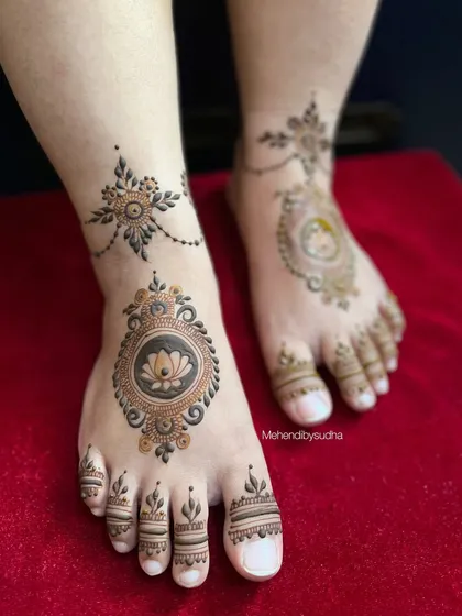 The minimalist lotus mandala design shown against a red background, highlighting the fresh henna paste.