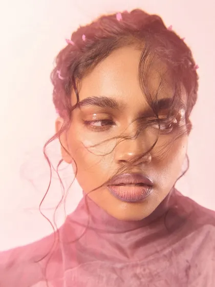 A soft and emotive beauty portrait with a focus on natural skin and hair texture. The gentle lighting and wind-blown hair create a feeling of effortless beauty.