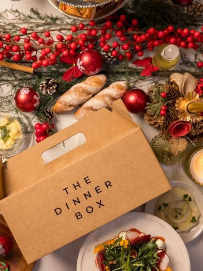 Our signature packaging is designed to protect the integrity of your meal and build anticipation for the feast within. Here, our box is pictured as part of a festive tablescape, ready to be the star of the celebration.