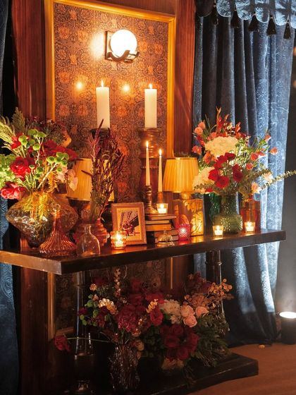A beautifully styled console table from the "Golden Rails" event, featuring vintage props, family photos, and lush floral arrangements to create an intimate, story-filled nook.