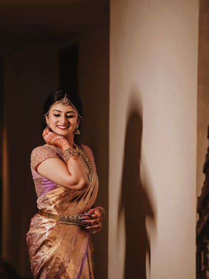 Bride Ishwarya in a quiet moment before her ceremony. The soft lighting highlights the beautiful fall of her reception saree.