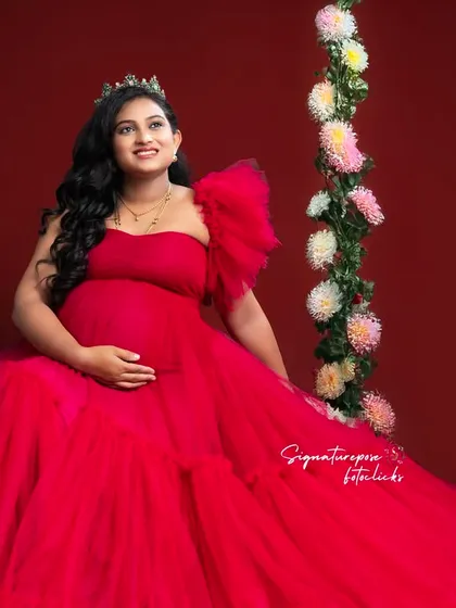 A sweet and regal portrait on a floral swing, combining the bold red gown with a touch of playful romance.