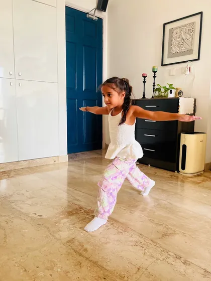 A young student holds the warrior pose, a foundational yoga asana that we incorporate into our dance classes to build strength and balance.