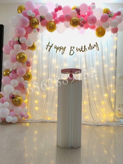 A lovely backdrop for a home party, using a curtain of fairy lights and a pink and gold balloon arch.