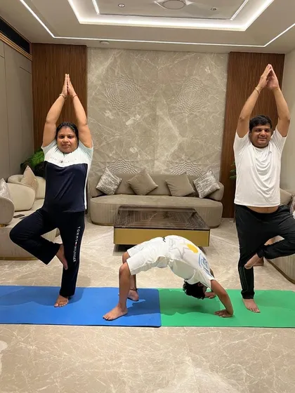 A fun moment from a home session with a family, where everyone is practicing different poses like Vrikshasana (Tree Pose) and Chakrasana (Wheel Pose).