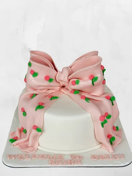A cake that's wrapped like a present. This design features a large, cascading pink fondant bow decorated with tiny, hand-piped roses.