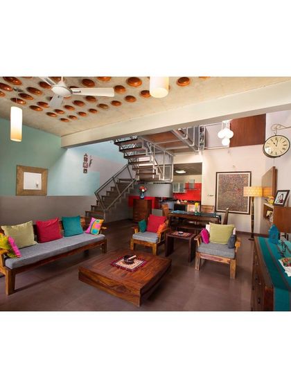 The living room of the Interlocking House showcases a terracotta pot filler slab ceiling, an innovative and sustainable technique that adds texture and character. The space is eclectic and colorful, reflecting the personality of its inhabitants.