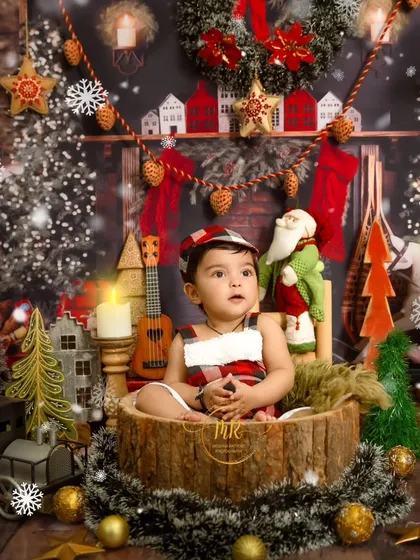 A Christmas-themed shoot with a baby sitting in a log-like basket, surrounded by a beautifully decorated fireplace scene.