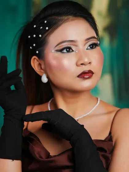 A high-fashion look with graphic white eyeliner, pearl hair accessories, and a bold, confident pose.