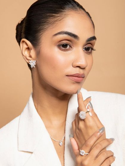 A sophisticated and professional look, showcasing how the jewelry can be styled with a blazer. This image is perfect for a brand targeting the modern working woman. The lighting is clean and bright, emphasizing the jewelry's sparkle.