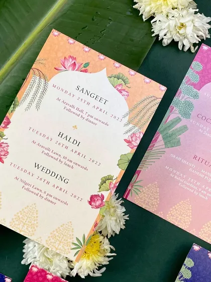 A vibrant invitation suite featuring a mix of bright colors and traditional Indian motifs. The design for the Sangeet, Haldi, and Wedding uses lotus flowers, palm trees, and intricate patterns.