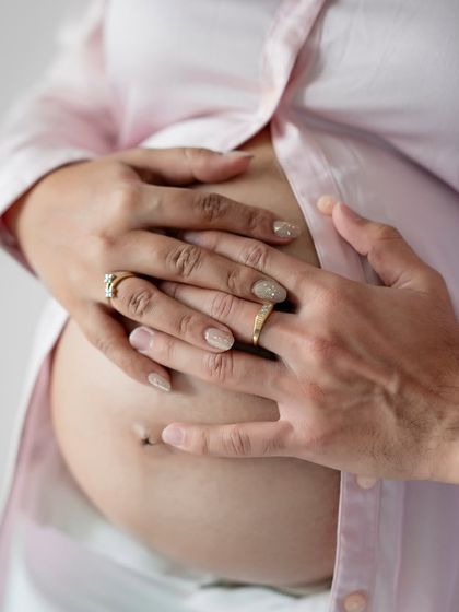 A detailed close-up of the parents' hands cradling the baby bump, a simple and powerful image of family connection.