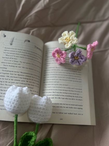 My handmade flowers make the perfect, aesthetic bookmark or decor piece. Here are some of my single stems, including white tulips and colorful forget-me-nots, resting on an open book.