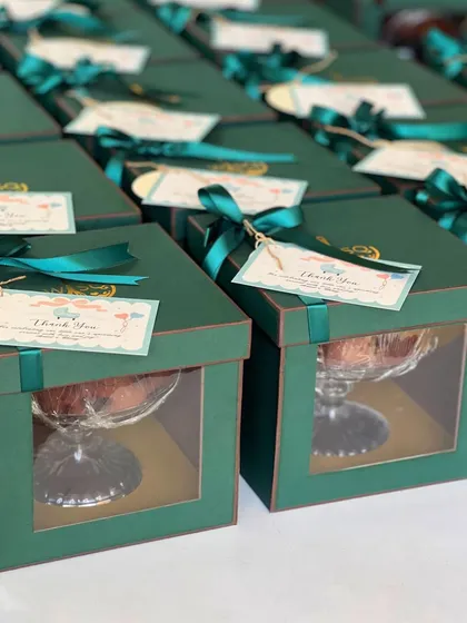 Our packaging is designed to impress. These emerald green gift boxes, complete with window displays, satin ribbons, and custom "Thank You" tags, were created for a client's special event. Each box securely holds one of our glass dessert cups, ensuring it looks as good as it tastes.
