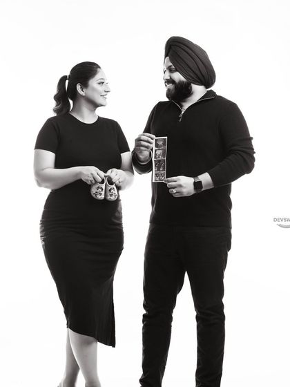 A beautiful black and white portrait of a couple sharing their excitement. They hold up both the sonogram and a pair of baby shoes, capturing all the details of their journey.