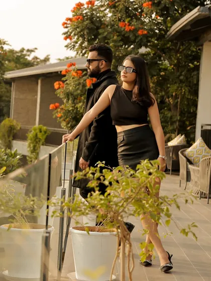 A chic and fashionable portrait of the couple on a modern veranda. Their confident poses and coordinated black outfits exude a cool, urban elegance.