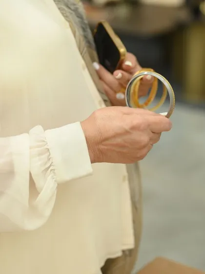 A guest holds the Altruist Kada bracelet, feeling its weight and admiring the etched design.