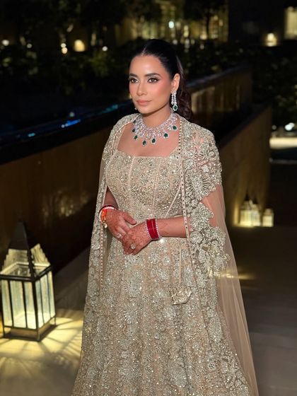 The bride's reception look captured in the warm evening light. Her makeup is radiant and polished, with a soft smoky eye that enhances her features beautifully.